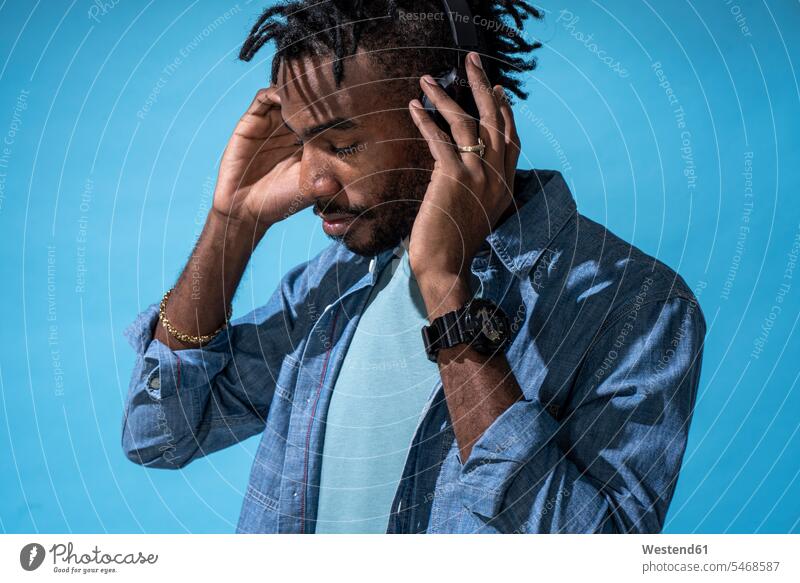 Porträt eines stilvollen jungen Mannes, der mit Kopfhörern Musik hört Disk-Jockey Disk-Jockeys Diskjockey Diskjockeys DJs Uhren Armbanduhren Kopfhoerer