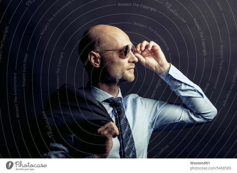 Porträt eines glatzköpfigen Geschäftsmannes mit Sonnenbrille vor einem schwarzen Hintergrund Businessmann Businessmänner Geschäftsmänner Glatze Glatzen kahl