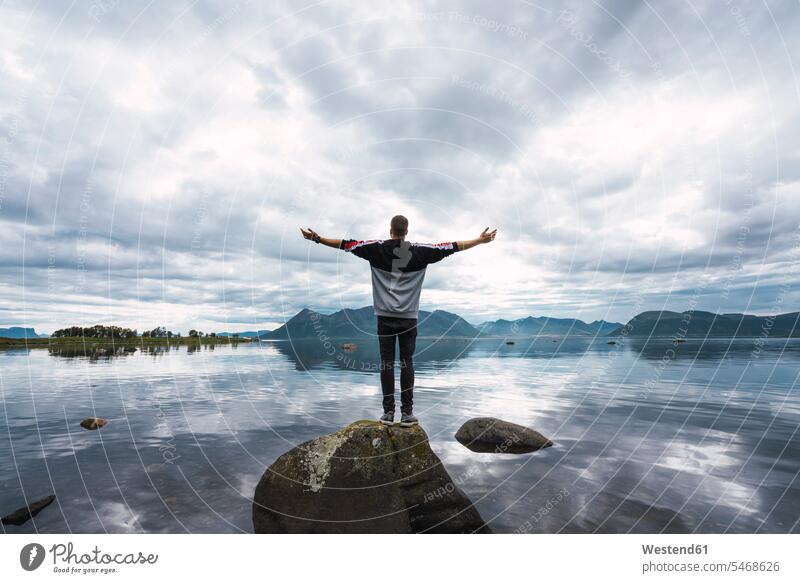 Norwegen, Insel Senja, Rückansicht eines Mannes, der auf einem Felsen an der Küste steht Männer männlich Kueste Kuesten Küsten stehen stehend Erwachsener