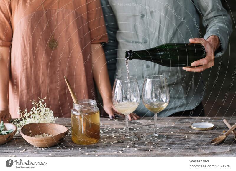 Ein Mann gießt Wein in ein Glas, während er mit seiner Freundin einen Cocktail zubereitet Farbaufnahme Farbe Farbfoto Farbphoto Innenaufnahme Innenaufnahmen