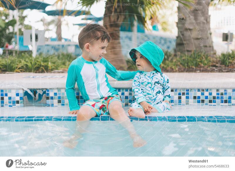 Glückliche kleine Brüder an einem Schwimmbad sitzend sitzt sommerlich Sommerzeit entspannen relaxen entspanntheit relaxt freuen geniessen Genuss glücklich sein