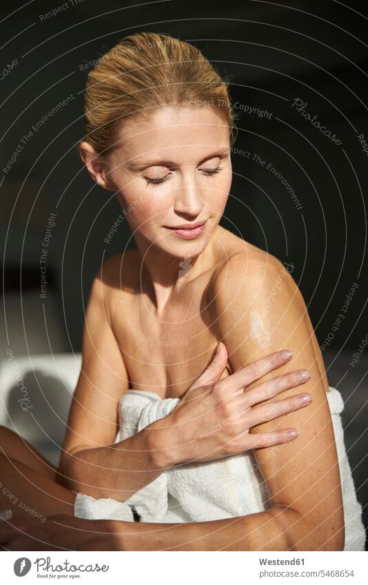 Porträt einer schönen Frau, die Hautcreme auf ihren Arm aufträgt Modell Modelle Models Handtuecher Handtücher Cremes Betten cremen entspannen relaxen