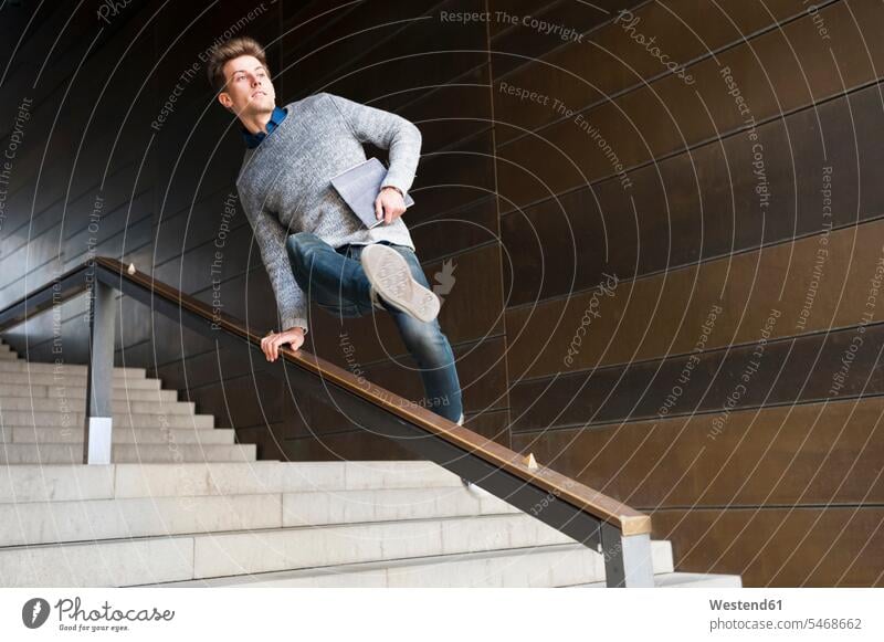 Junger Mann springt auf Stufen im unterirdischen Gang über das Geländer Farbaufnahme Farbe Farbfoto Farbphoto Innenaufnahme Innenaufnahmen innen drinnen Tag