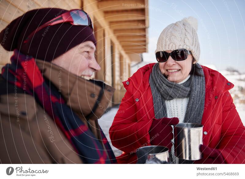 Glückliches reifes Paar mit heissen Getränken im Winter auf einer Berghütte im Freien Pärchen Paare Partnerschaft glücklich glücklich sein glücklichsein