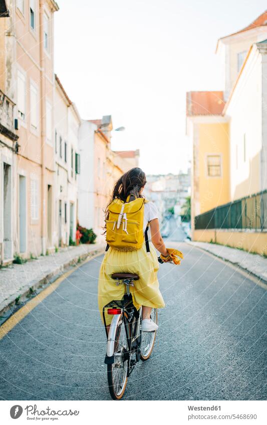Frau mit Rucksack fährt Fahrrad auf der Straße inmitten von Gebäuden in der Stadt Farbaufnahme Farbe Farbfoto Farbphoto Portugal Freizeitbeschäftigung Muße Zeit