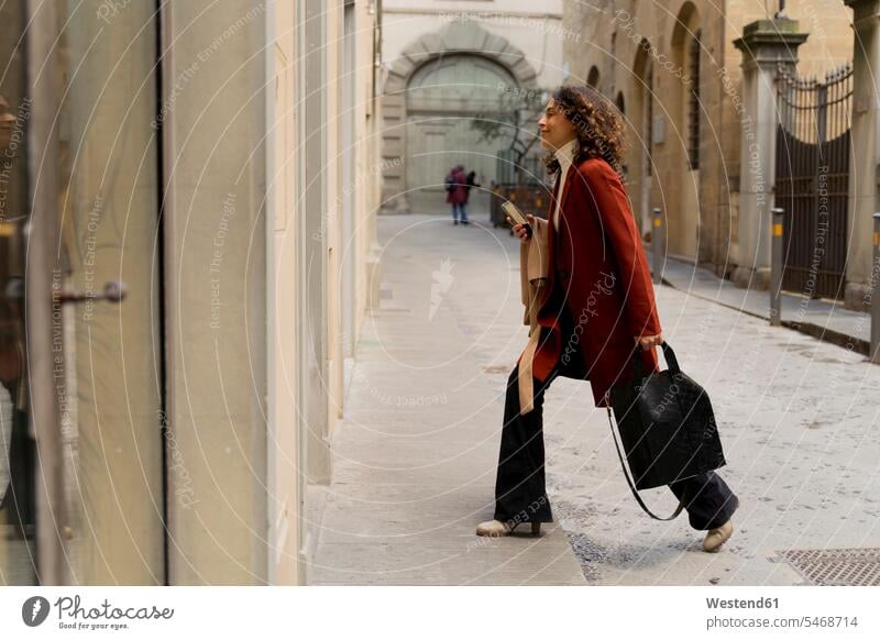 Frau geht in einer Gasse in der Stadt, Florenz, Italien Leute Menschen People Person Personen gelockt gelockte Haare gelocktes Haar lockig lockiges Haar Taschen