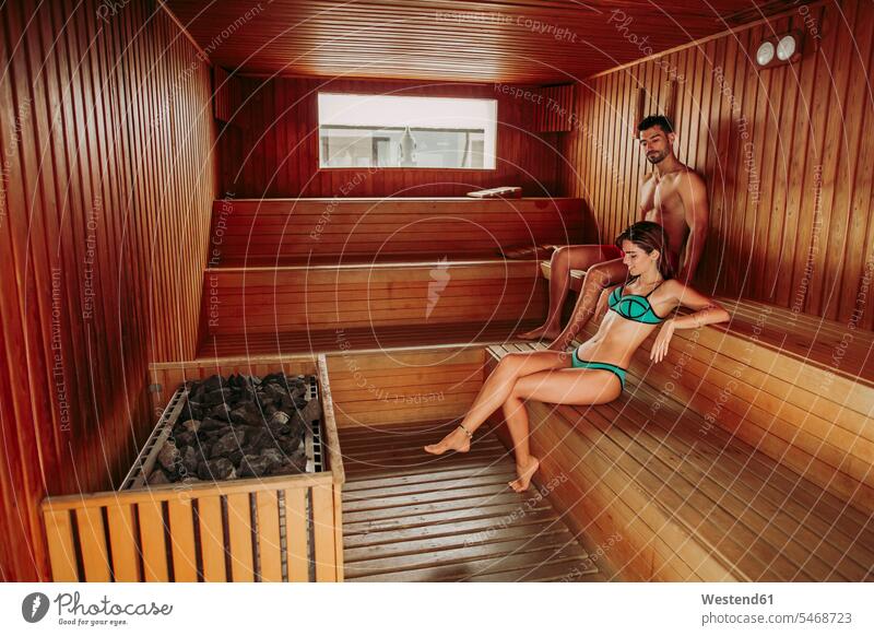 Paar entspannt in einer Sauna (value=0) Badebekleidung Bikinis entspannen relaxen sitzend sitzt entspanntheit relaxt geniessen Genuss heiss Hitze Muße