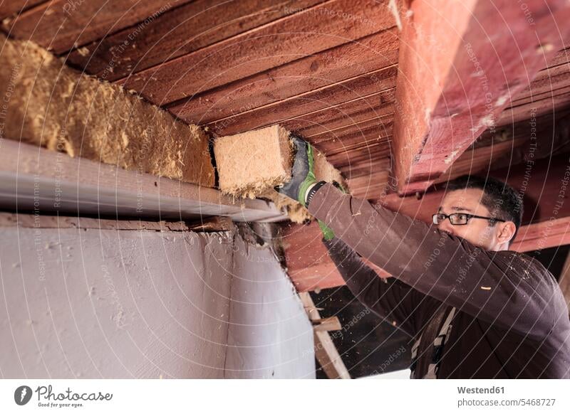 Dachisolierung, Arbeiter füllen Schrägdach mit Holzfaserisolierung abfüllen Füllung Dachdämmung dämmen isolieren Dämmplatte Dämmplatten Dämmung Job Sanierung