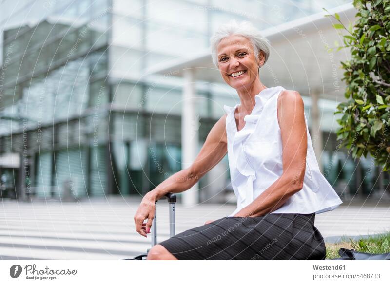Porträt einer glücklichen älteren Frau mit Gepäck in der Stadt sitzend Glück glücklich sein glücklichsein weiblich Frauen Seniorin Seniorinnen alt sitzt