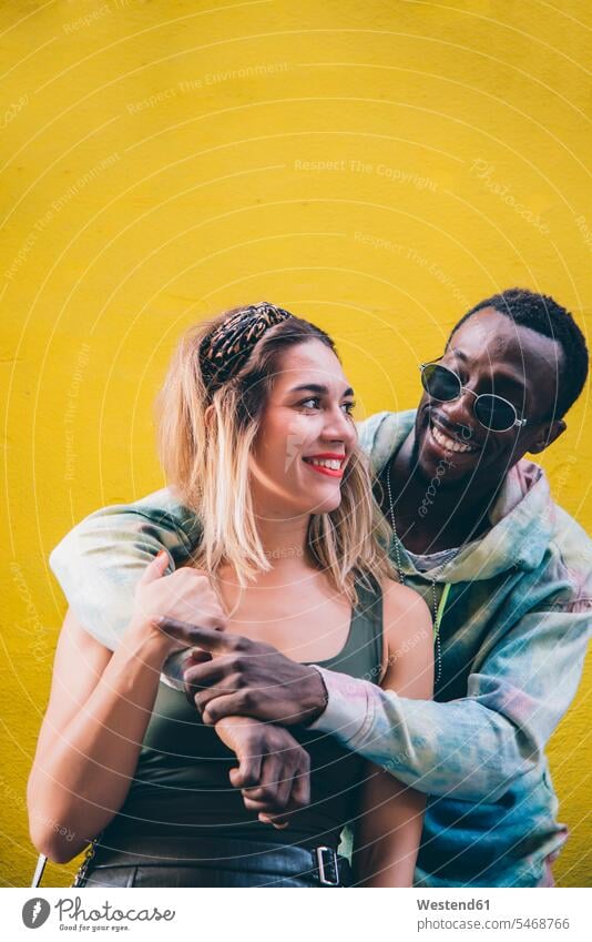 Porträt eines glücklichen Paares vor der gelben Wand Leute Menschen People Person Personen Afrikanisch Afrikanische Abstammung dunkelhäutig Farbige Farbiger