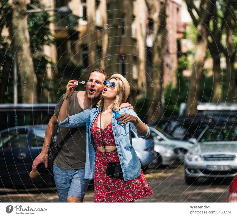 Ein Paar, das gemeinsam Seifenblasen in der Stadt bläst staedtisch städtisch Gemeinsam Zusammen Miteinander Pärchen Paare Partnerschaft pusten Außenaufnahme