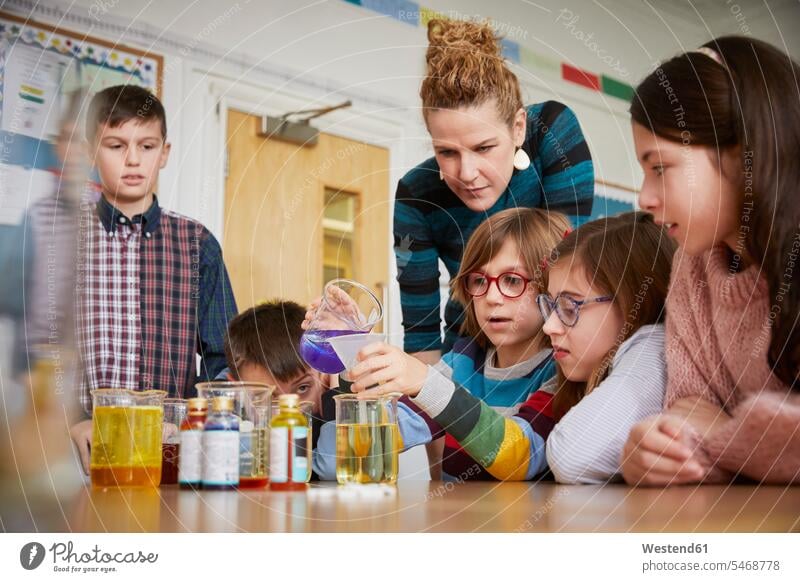 Kinder in einer naturwissenschaftlichen Unterrichtsstunde mit einem Lehrer Team Lehrerin Schüler lernen Flüssigkeit Chemie Gemeinsam Test Zusammenarbeit Schule