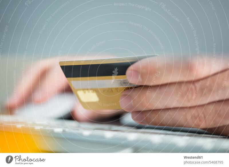 Mann macht Online-Zahlung mit Kreditkarte, Nahaufnahme EC-Karte Kreditkarten bezahlen Schreibtisch Arbeitstisch Schreibtische Männer männlich bargeldlos