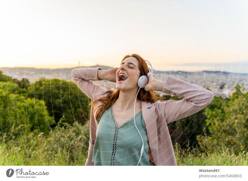 Junge rothaarige Frau mit Kopfhörer auf Aussichtspunkt Kopfhoerer hoeren Jubel abends begeistert Enthusiasmus enthusiastisch Überschwang Überschwenglichkeit