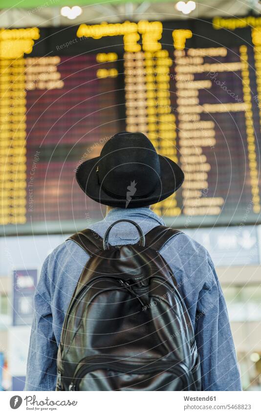 Junger Mann mit Hut und Rucksack Blick auf Ankunft Abflug Bord am Flughafen Hüte schauen sehend Männer männlich Fluginformationstafel Flug-Informationstafel