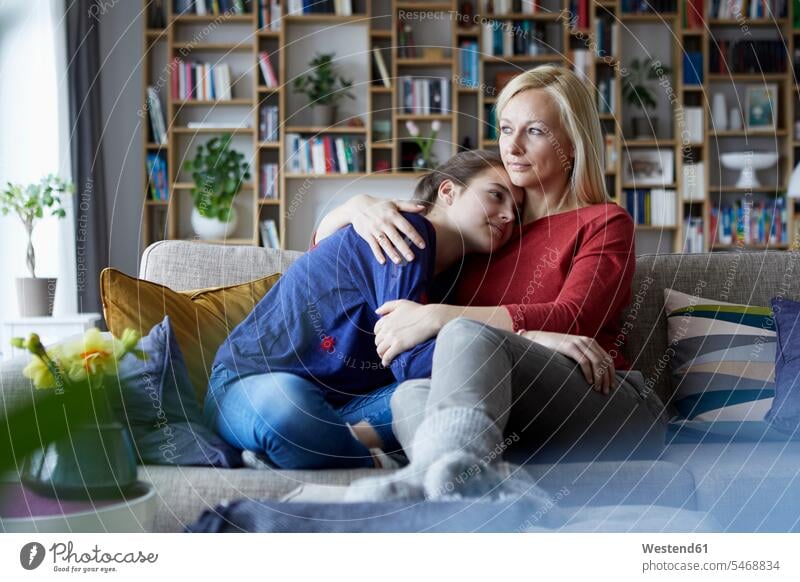 Mutter und halbwüchsige Tochter sitzen auf dem Sofa und legen die Arme um Europäer Kaukasier Europäisch kaukasisch Hygge hyggelig Geborgenheit geborgen behütet