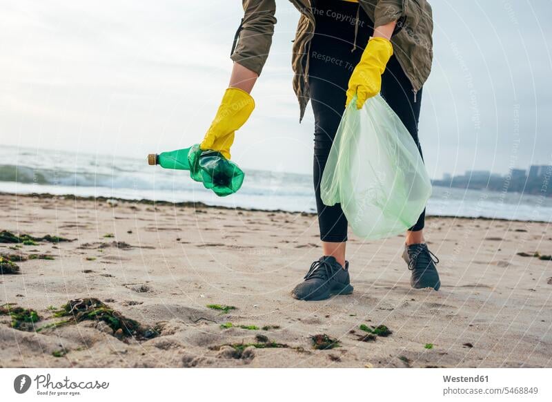 Umweltschützerin mit Müllbeutel reinigt Strand, während sie gegen klaren Himmel steht Farbaufnahme Farbe Farbfoto Farbphoto Außenaufnahme außen draußen