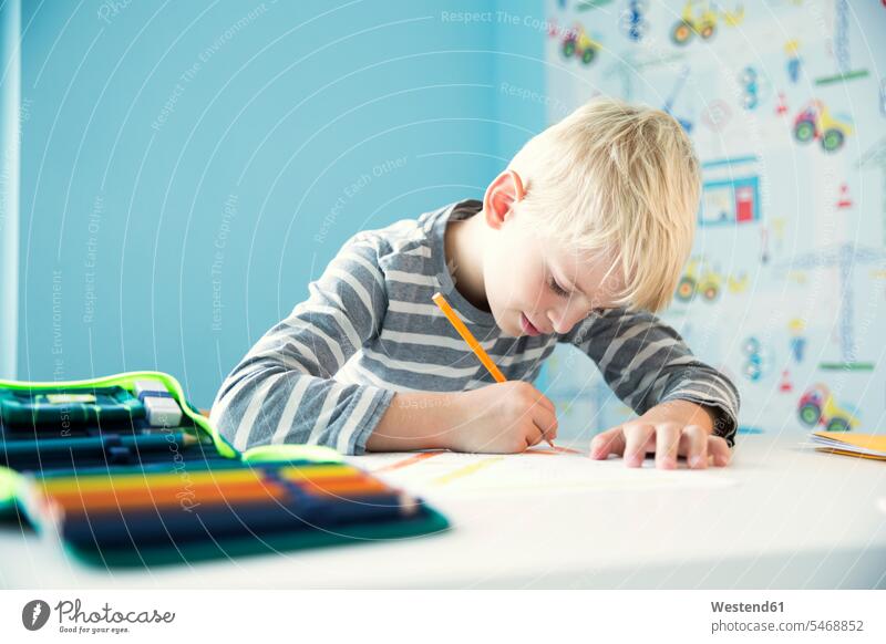 Konzentrierter Junge macht Hausaufgaben am Schreibtisch im Kinderzimmer fokussiert Zimmer Tisch Mensch Aufmerksamkeit Schulheft Federmappe Buntstift Pflicht