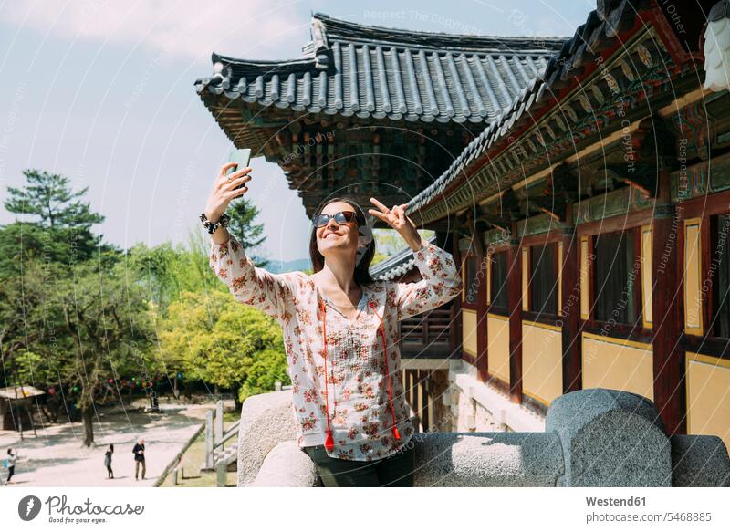 Südkorea, Gyeongju, glückliche Frau macht ein Selfie mit Handy im Bulguksa-Tempel Glück glücklich sein glücklichsein weiblich Frauen Selfies Mobiltelefon