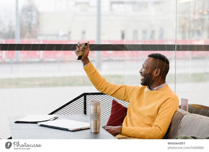 Glücklicher Mann benutzt Smartphone in einem Cafe geschäftlich Geschäftsleben Geschäftswelt Geschäftsperson Geschäftspersonen Businessmann Businessmänner