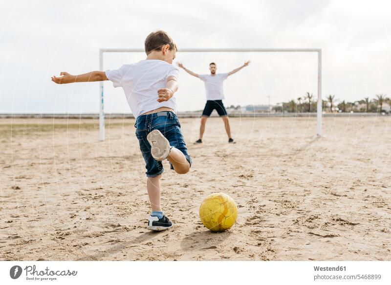 Mann und Junge spielen Fussball am Strand T-Shirts Bälle Fußbälle sommerlich Sommerzeit freuen Glück glücklich sein glücklichsein Farben Farbtoene Farbton