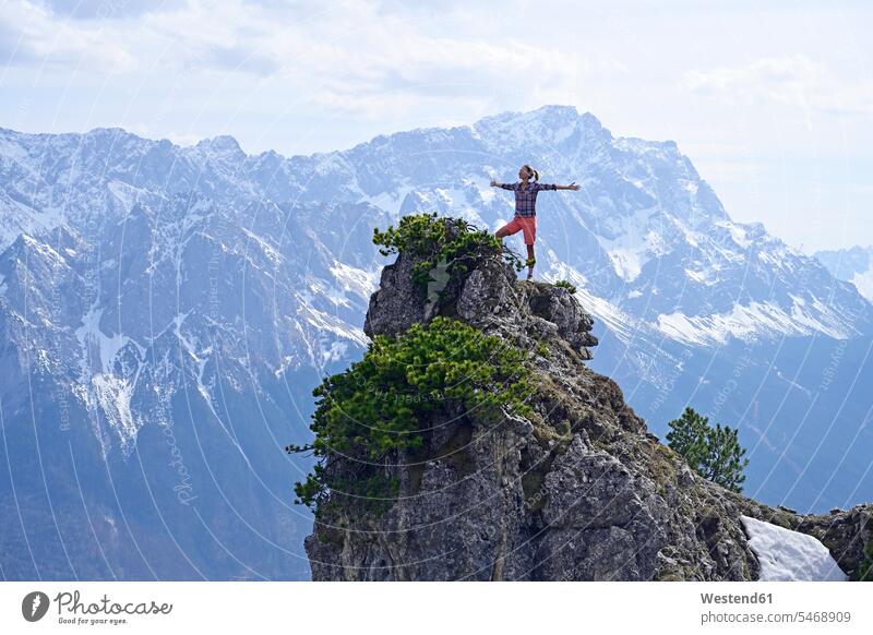 Frau steht mit ausgestreckten Armen auf felsigem Berggipfel und schaut Landschaft gegen den Himmel Farbaufnahme Farbe Farbfoto Farbphoto Außenaufnahme außen