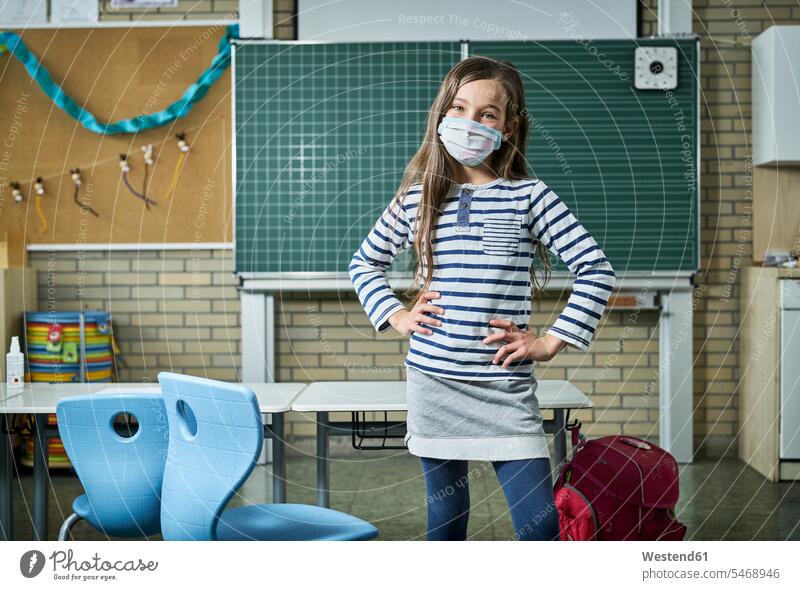 Porträt eines selbstbewussten Mädchens mit Maske im Klassenzimmer Ausbildung Schueler Schulkinder Schüler Schultafel Schultafeln stehend steht Gesund geschützt