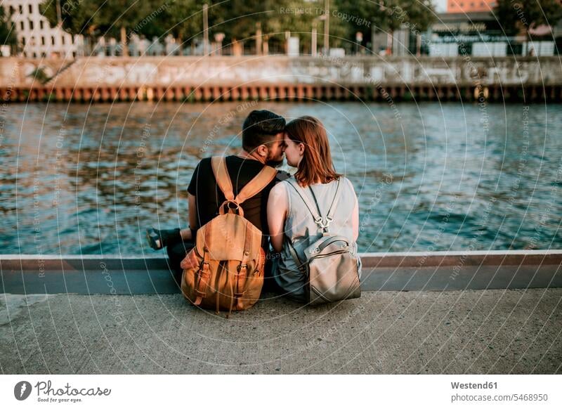 Liebevolles junges Paar an der Spree, Berlin, Deutschland Touristen Rucksäcke knuddeln schmusen sitzend sitzt Jahreszeiten sommerlich Sommerzeit entspannen