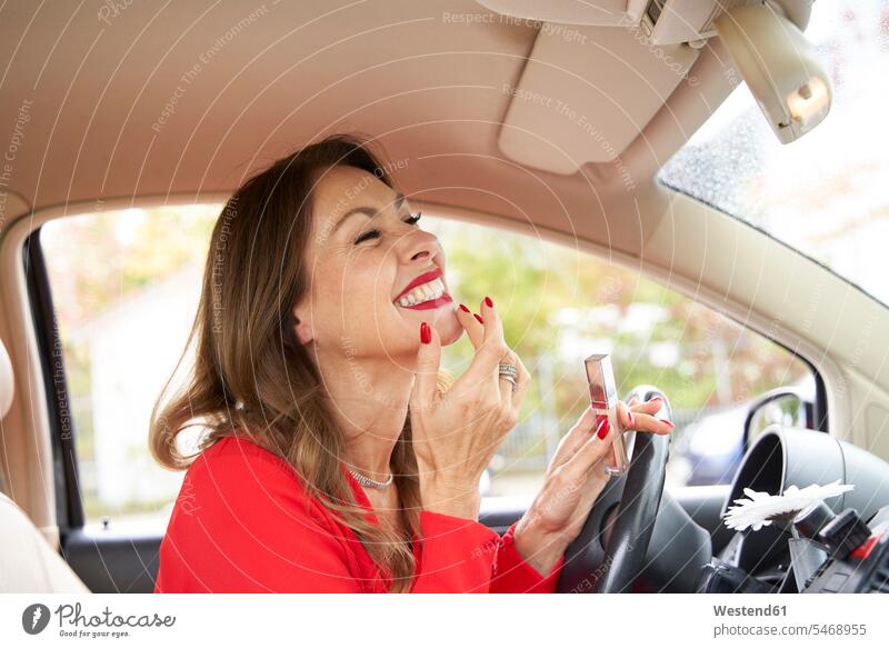 Reife Frau mit roten Lippen und Nägeln im Auto Kleider Rückspiegel KFZ Verkehrsmittel Automobil Autos PKW PKWs Wagen fahrend fahrende fahrender fahrendes