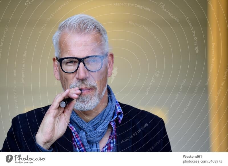 Porträt eines reifen Mannes, der eine elektronische Zigarette raucht Zigaretten gut gekleidet Smart Casual gut angezogen Geschäftskleidung Raucherthemen