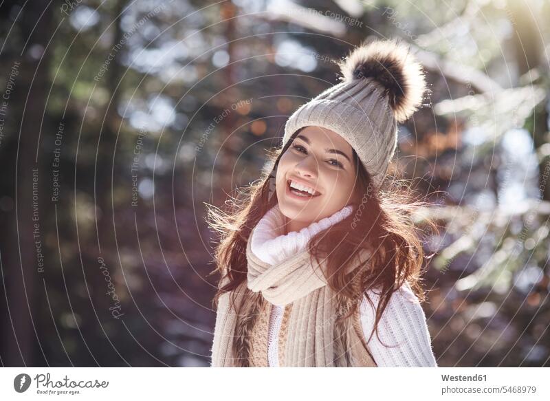 Porträt einer lachenden jungen Frau mit Strickwaren im Winterwald weiblich Frauen Portrait Porträts Portraits winterlich Winterzeit gestrickt Wald Forst Wälder