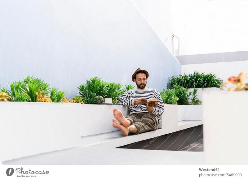 Mann sitzt auf dem Balkon und liest ein Buch Leute Menschen People Person Personen Europäisch Kaukasier kaukasisch 1 Ein ein Mensch eine nur eine Person single