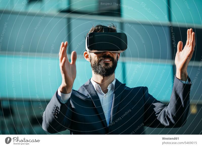 Geschäftsmann mit Virtual-Reality-Brille vor dem Bürogebäude Bürohaus Bürohäuser Brillen Virtuelle Realität Virtuelle Realitaet VR Businessmann Businessmänner