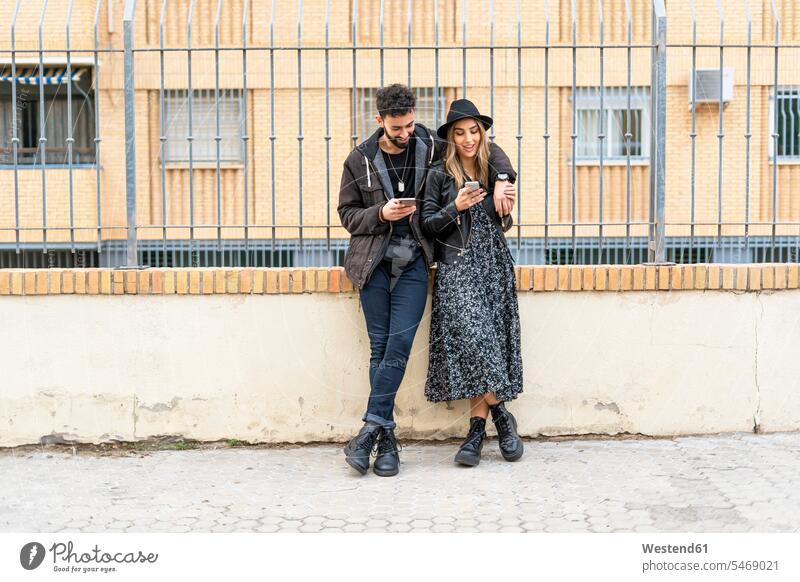Junges Ehepaar in der Stadt bei der Benutzung ihres Mobiltelefons Leute Menschen People Person Personen Europäisch Kaukasier kaukasisch 2 2 Menschen 2 Personen