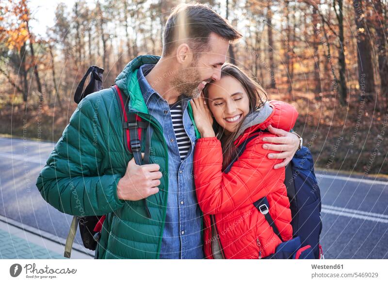 Glückliches Paar umarmt auf einer Straße in den Wäldern während Rucksacktour Wald Forst Ausflug Ausflüge Kurzurlaub Ausfluege glücklich glücklich sein