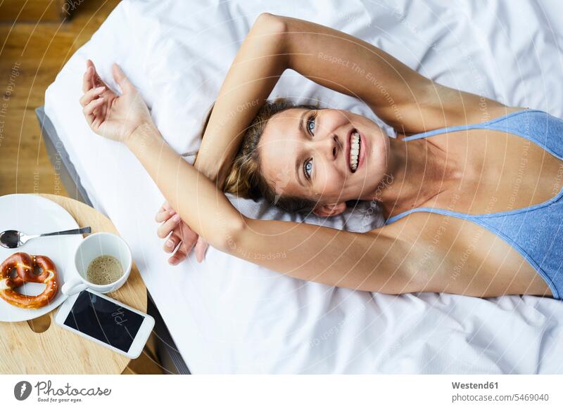 Porträt einer lachenden, im Bett liegenden jungen Frau Portrait Porträts Portraits weiblich Frauen Betten liegt positiv Emotion Gefühl Empfindung Emotionen