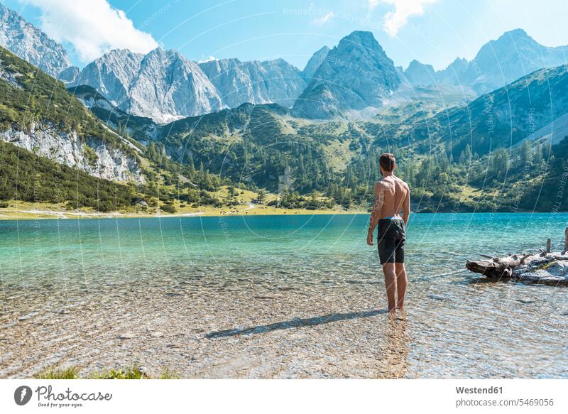 Österreich, Tirol, Junger Mann am Seebensee steht knöcheltief im Wasser Bergsee Bergseen Ruhe Beschaulichkeit ruhig reisen Travel verreisen Weg Reise Vitalität