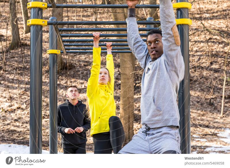Freunde trainieren in Affenbars in einem Park Klettergerüst Klettergeruest Fitness fit Gesundheit gesund Übung Uebung Übungen Uebungen Parkanlagen Parks Sport