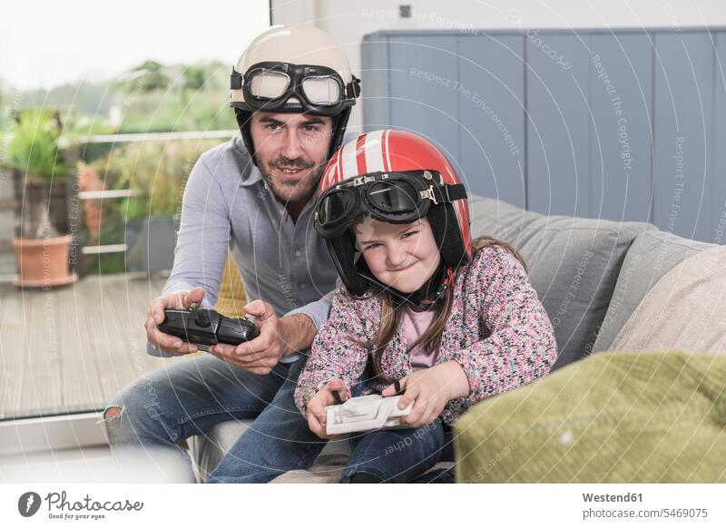 Junger Mann und kleines Mädchen tragen Biker-Helme, spielen Rennspiel mit Spielkonsolen Wettbewerb Wettkampf Konkurrenz Motorradhelm Motorradhelme Videospiel