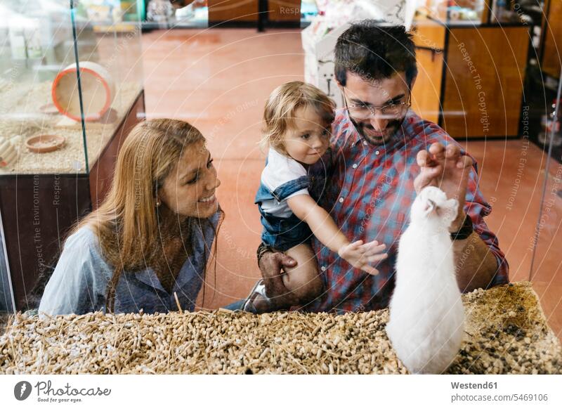Glückliche Familie beim Betrachten eines Kaninchens in einer Zoohandlung Leute Menschen People Person Personen Europäisch Kaukasier kaukasisch Südeuropäisch