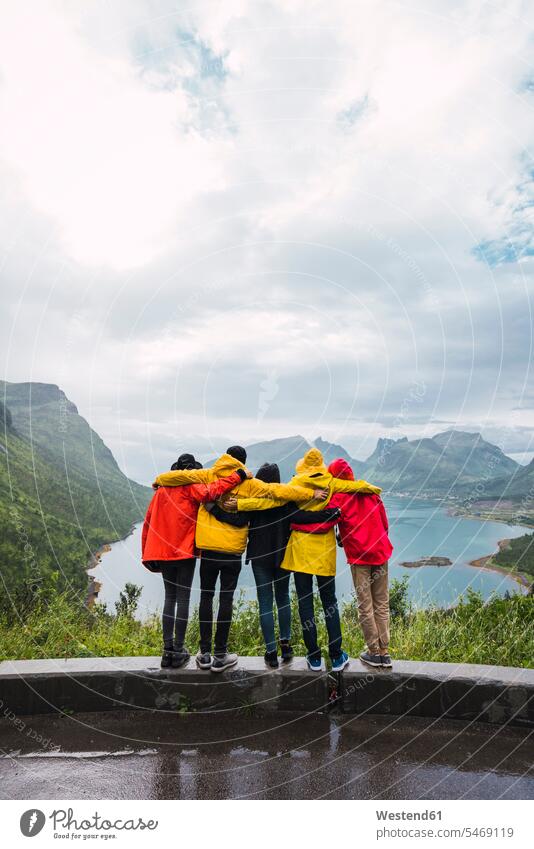 Norwegen, Insel Senja, Rückansicht von sich umarmenden Freunden auf einem Aussichtspunkt an der Küste stehen stehend steht Kueste Kuesten Küsten Umarmung