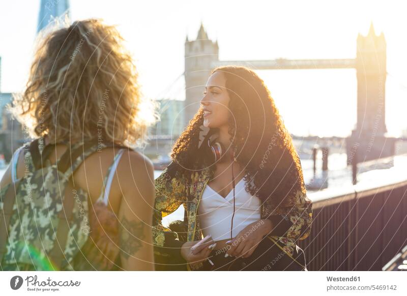 UK, London, zwei Freunde zusammen in der Stadt mit Tower Bridge im Hintergrund bei Sonnenuntergang Freundinnen Brücke Bruecken Brücken staedtisch städtisch