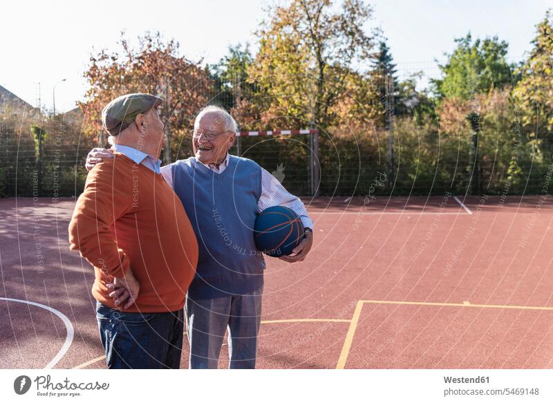 Zwei fitte Senioren haben Spaß auf einem Basketballfeld spielen sportlich Ball Bälle Beste Freunde Bester Freund lachen sprechen reden Sport Freundschaft