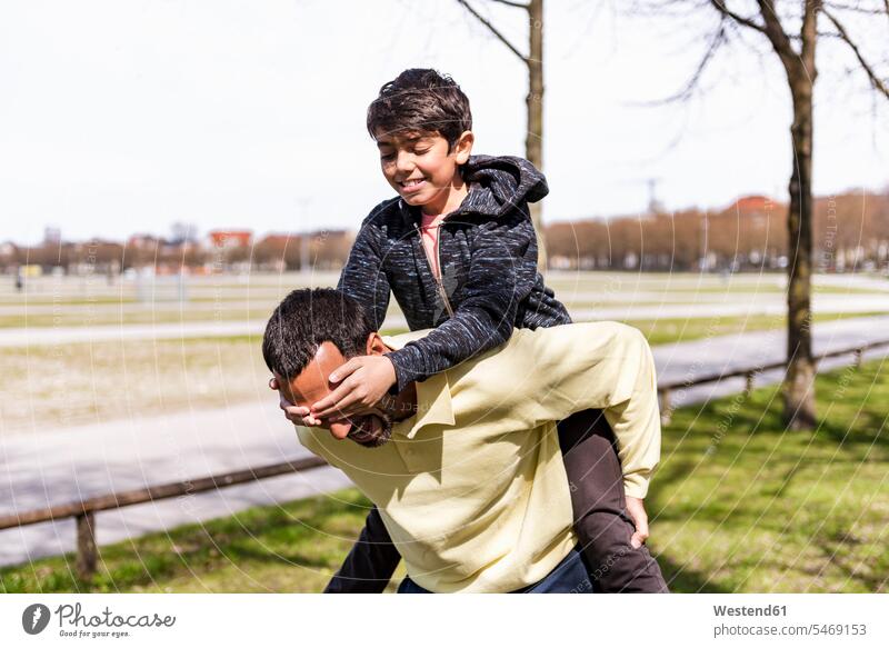 Glücklicher Vater trägt Sohn huckepack in einem Park Papas Väter Vati Vatis Papis Söhne Huckepack tragen transportieren glücklich glücklich sein glücklichsein