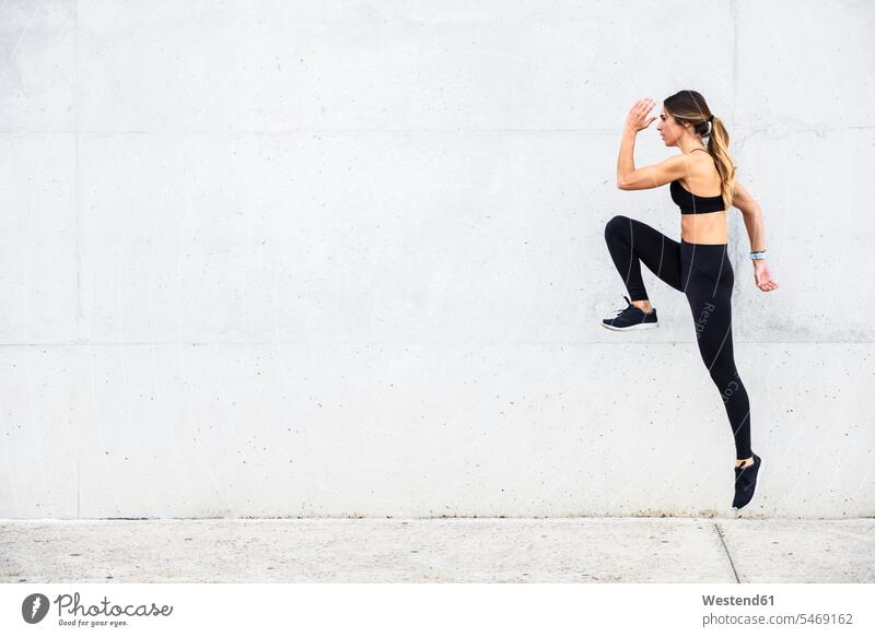 Athlet springt vor einer weißen Wand Mauer Mauern laufen rennen springen hüpfen üben ausüben Übung trainieren Workout Sportler sportlich Sportlerin