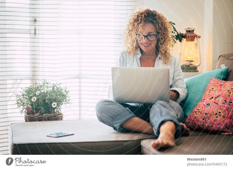 Lächelnde Frau mit Laptop auf der Couch zu Hause Gefärbtes Haar Gefärbte Haare Gemütlich Wohlfühlen behaglich Gemütlichkeit Zuhause arbeiten