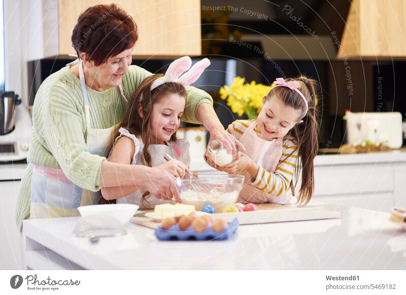 Großmutter und Enkelinnen backen gemeinsam Osterplätzchen in der Küche Enkeltochter Enkeltöchter Grossmutter Oma Grossmama Großmütter Omi Ostern Osterfest Keks