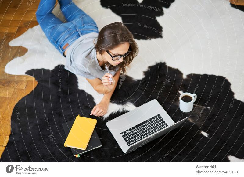 Junge Frau zu Hause auf dem Boden liegend mit Laptop Böden Boeden liegt Notebook Laptops Notebooks weiblich Frauen Zuhause daheim Computer Rechner Erwachsener