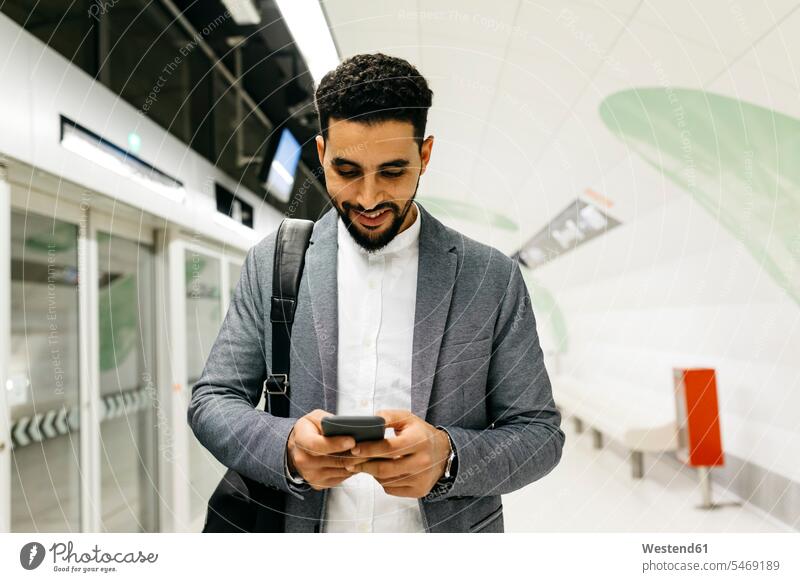Junger Geschäftsmann benutzt Mobiltelefon in U-Bahn-Station geschäftlich Geschäftsleben Geschäftswelt Geschäftsperson Geschäftspersonen Businessmann