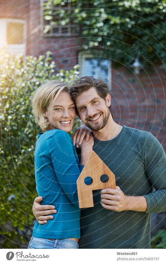 Porträt des glücklichen Paares vor ihrem Haus mit Hausmodell Pärchen Partnerschaft Glück glücklich sein glücklichsein Häuser Haeuser Modell Modelle Portrait